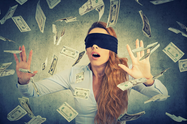 Blindfolded young entrepreneur  businesswoman trying to catch dollar bills