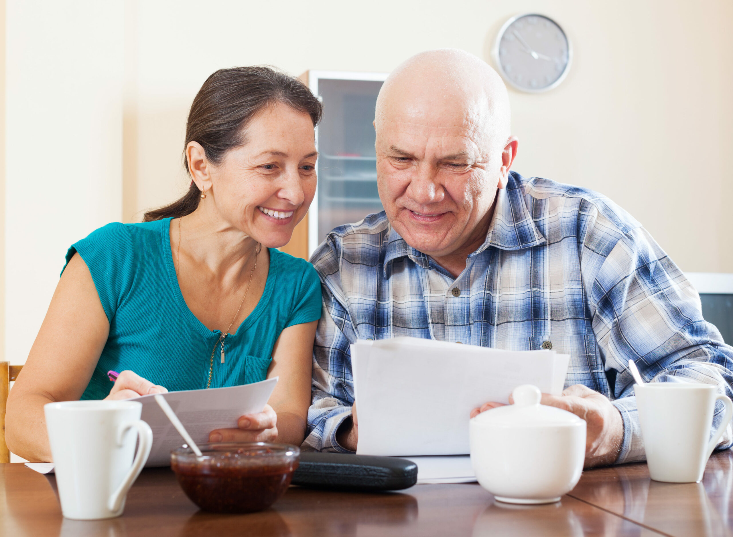 Smiling mature couple reading documents during tea