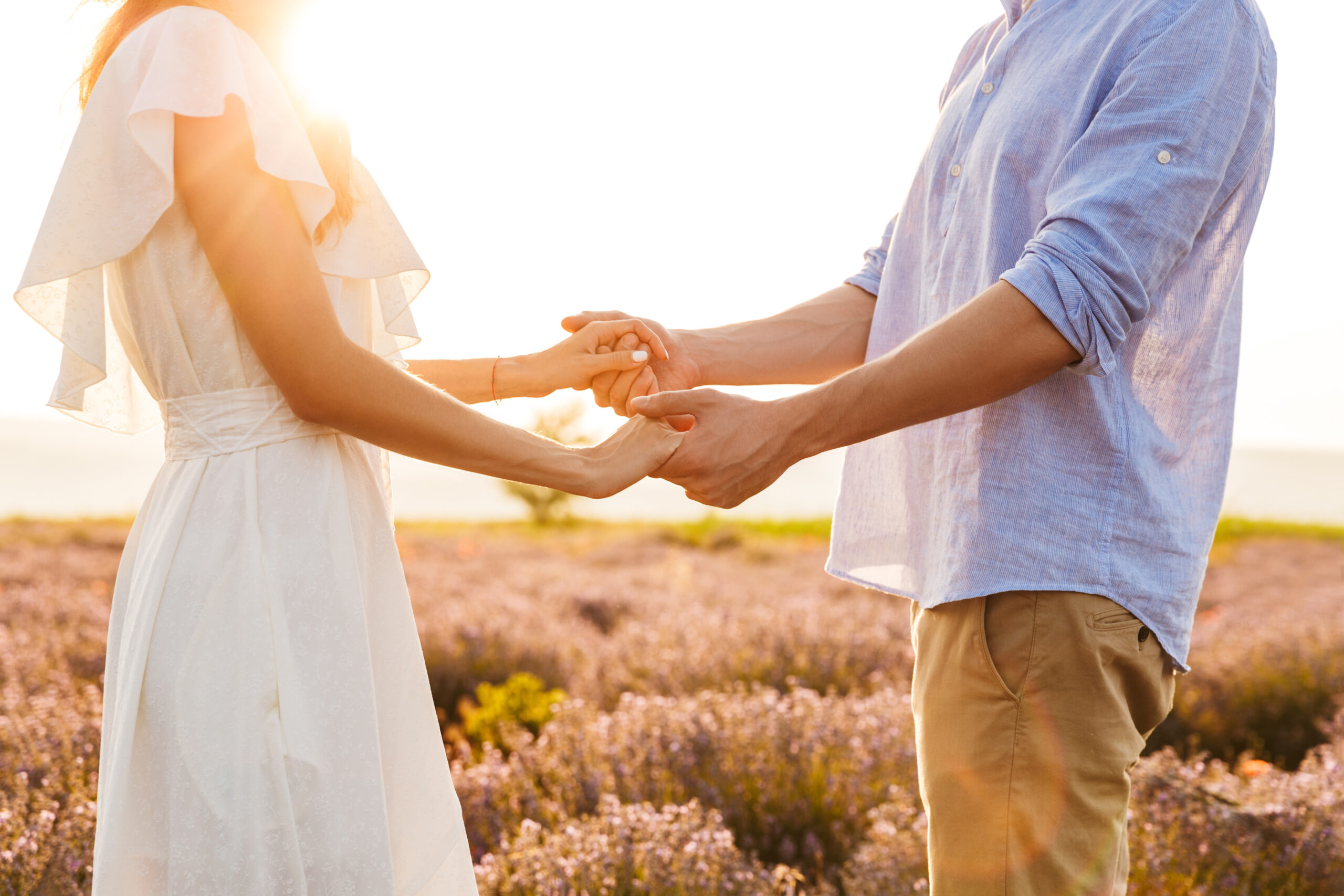 Cropped image of young couple man and woman holding hands, while