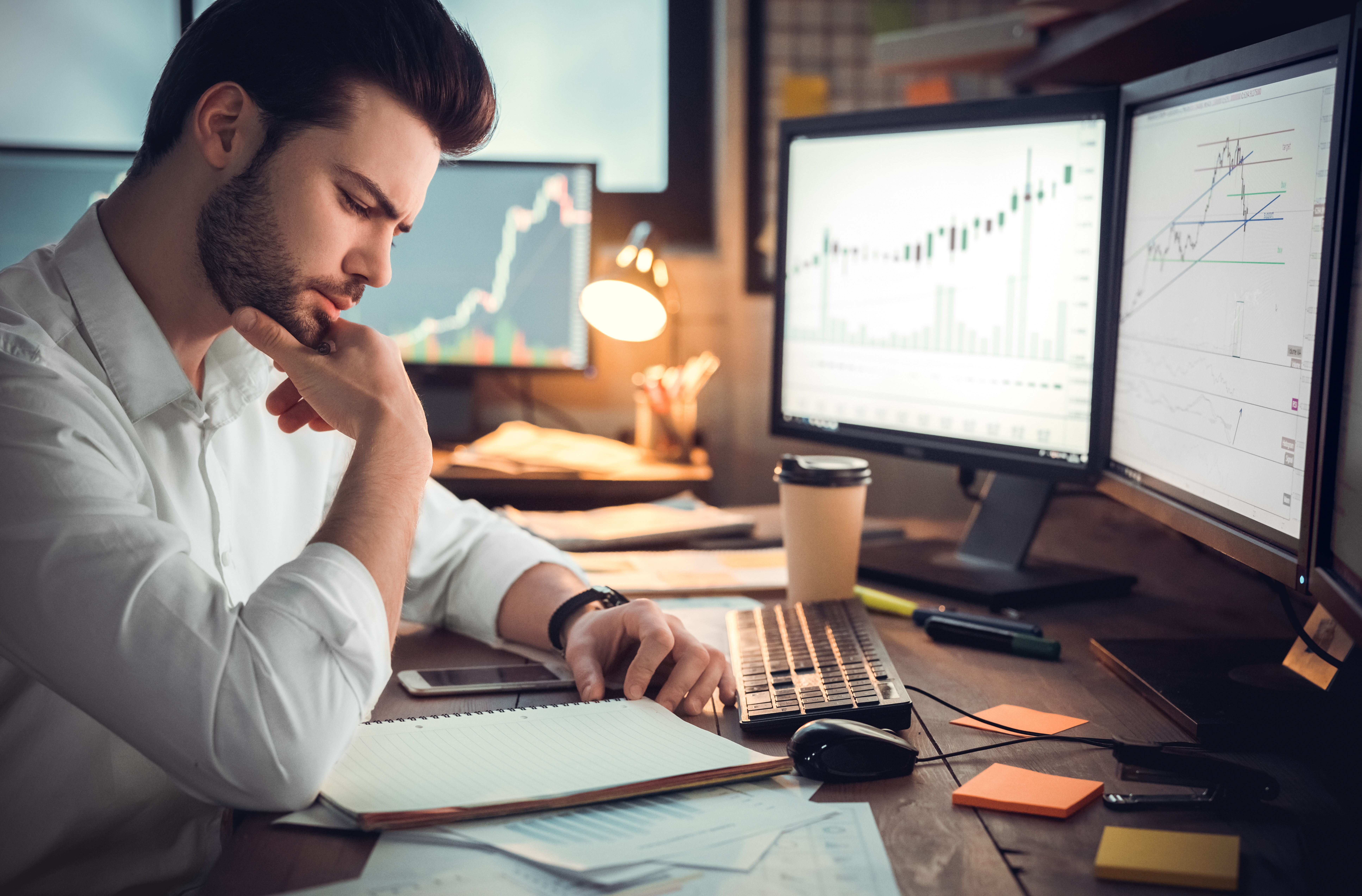 Young male trader at office work concept sitting browsing smartphone concentrated