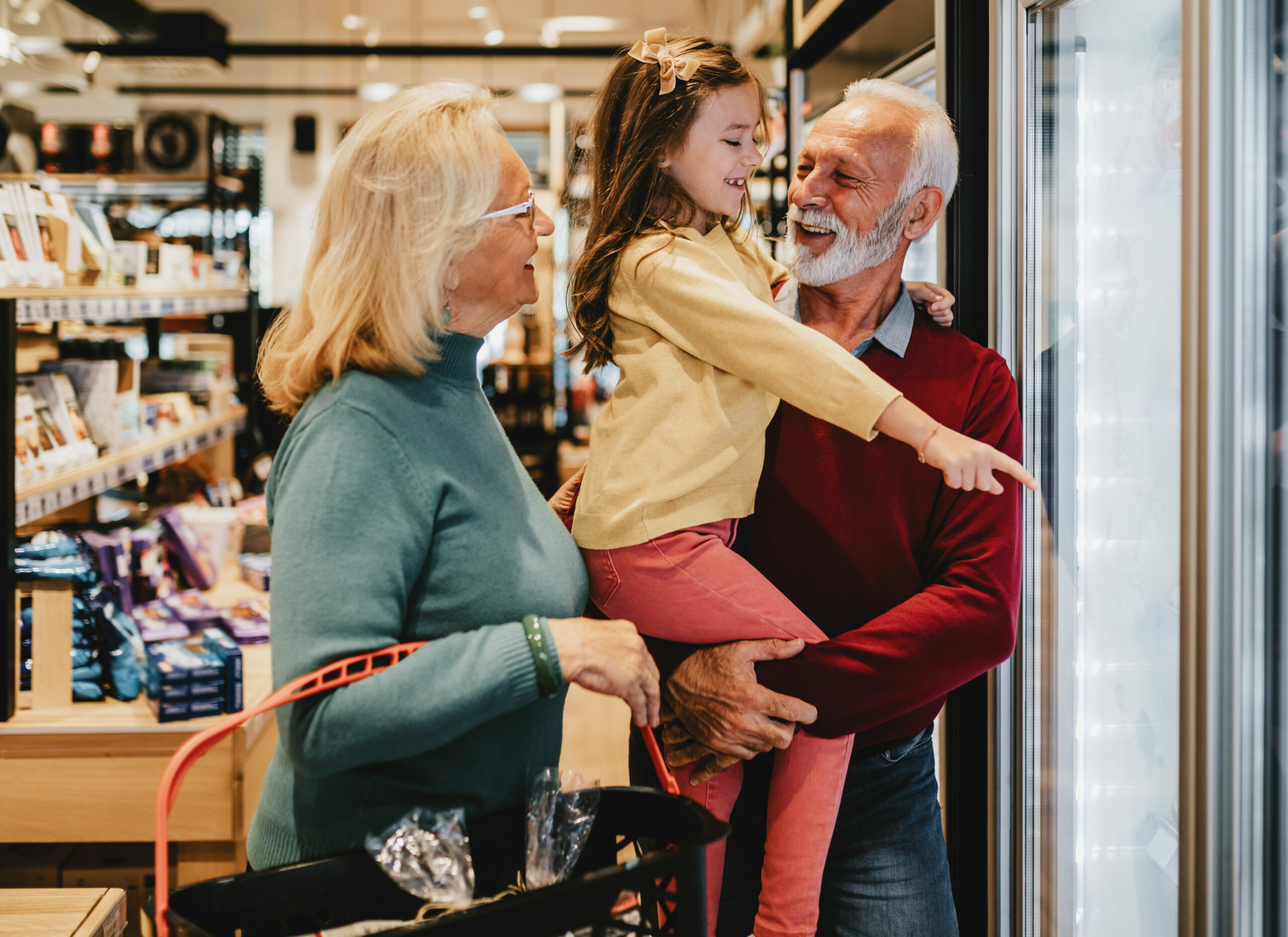 Happy grandmother and grandfather with granddaughter shopping to